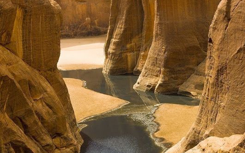 A placid stream threads its way between sheer rock cliffs.